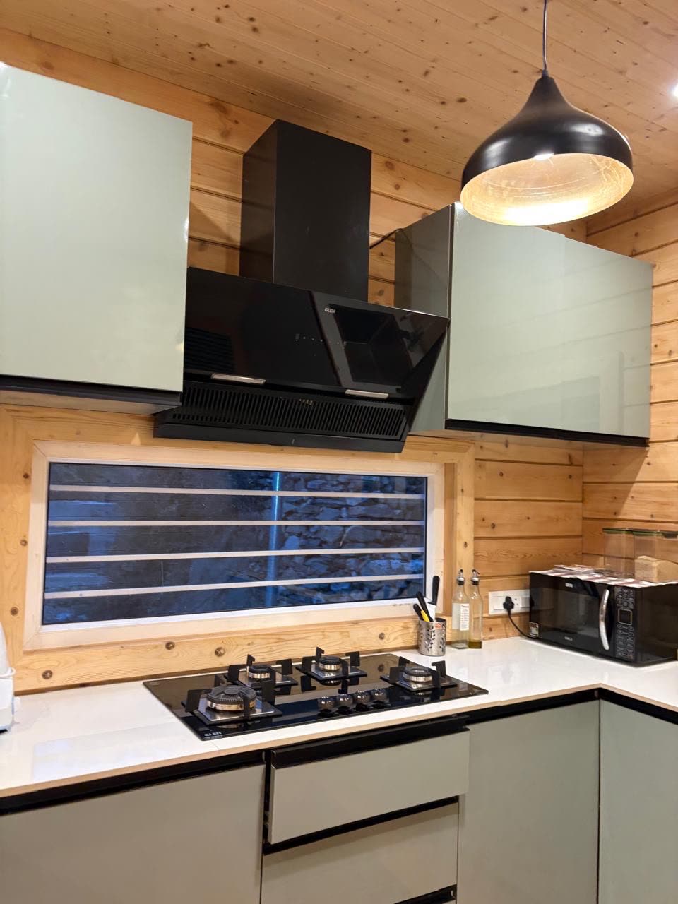 Modern modular kitchen with gas hob, chimney and a window onto the hills