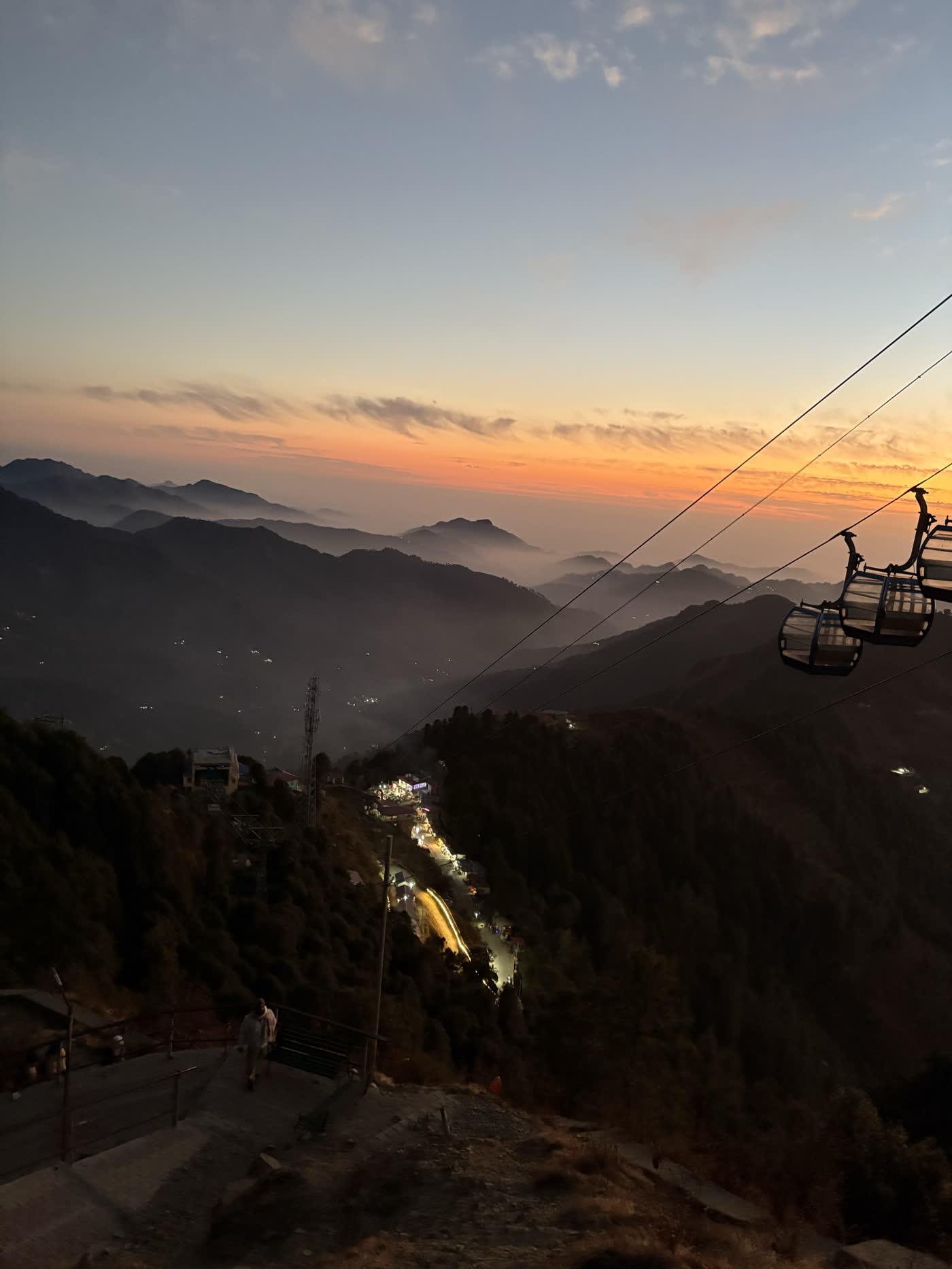 Cable car ropeway descending into a valley lit up at dusk, near Surkanda Devi