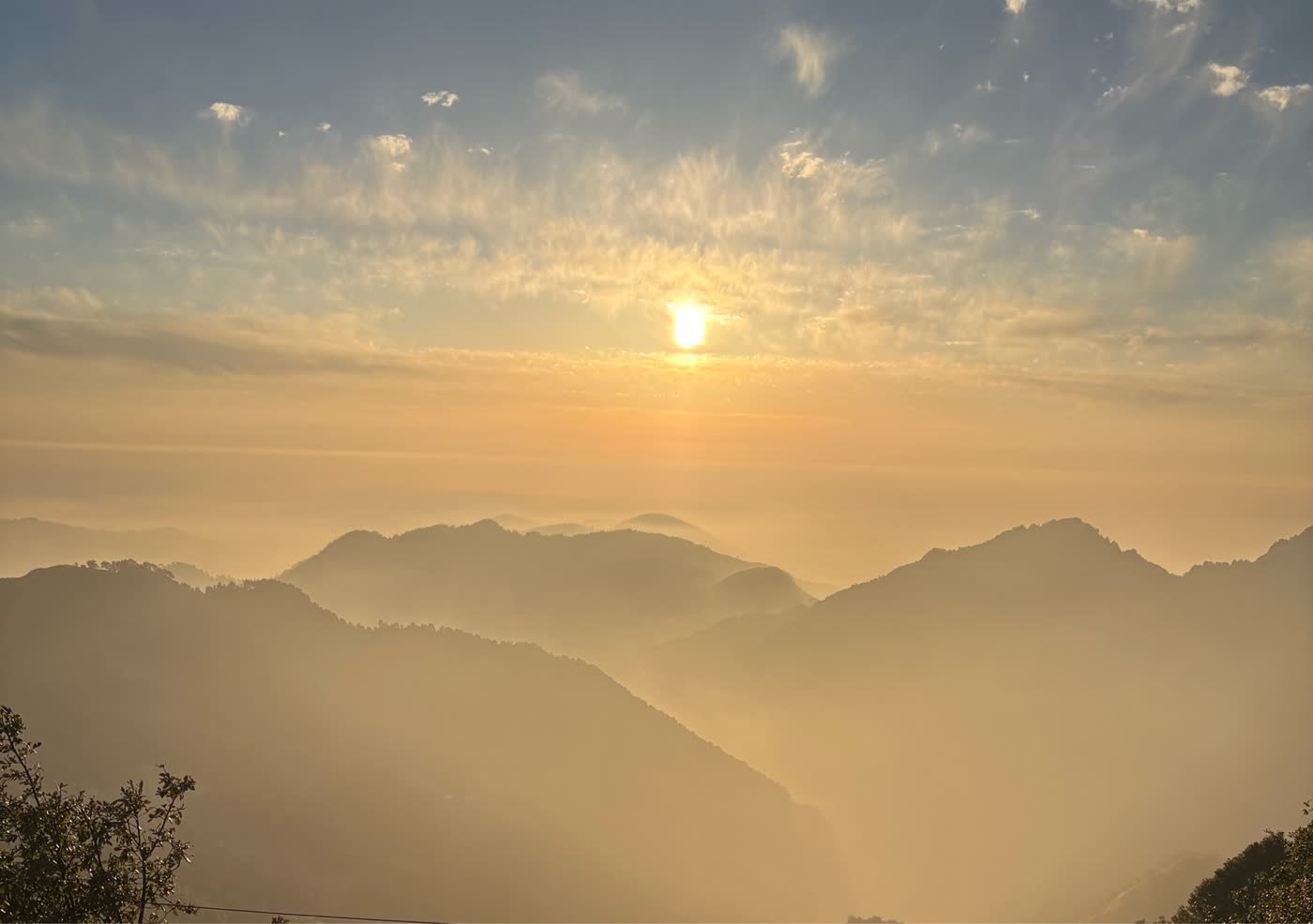 Golden sunrise spreading across layered Garhwal hills, seen from Surkanda Devi